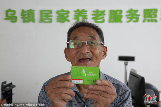 80歲的陳叔良老人在工作人員的指導下辦理樂享生活卡。他憑借此卡便可享受照料中心提供的線上線下服務。 (圖片作者：沈志成)