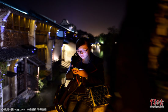 不管白天還是夜里，行走在烏鎮(zhèn)老街上，處處可見上網(wǎng)的人群。(圖片作者：梁臻)